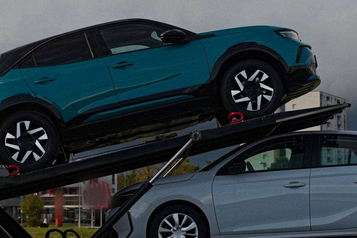 Twee wagens op een autotransporter: een blauwgroene bovenaan, een zilveren eronder