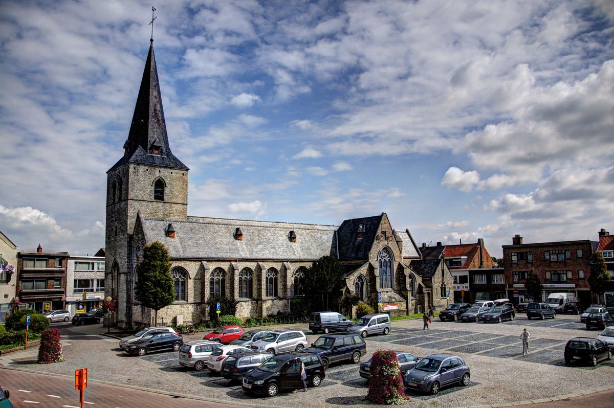 De Sint-Willibrorduskerk van Nijlen met het plein ervoor, onder een wolkenlucht